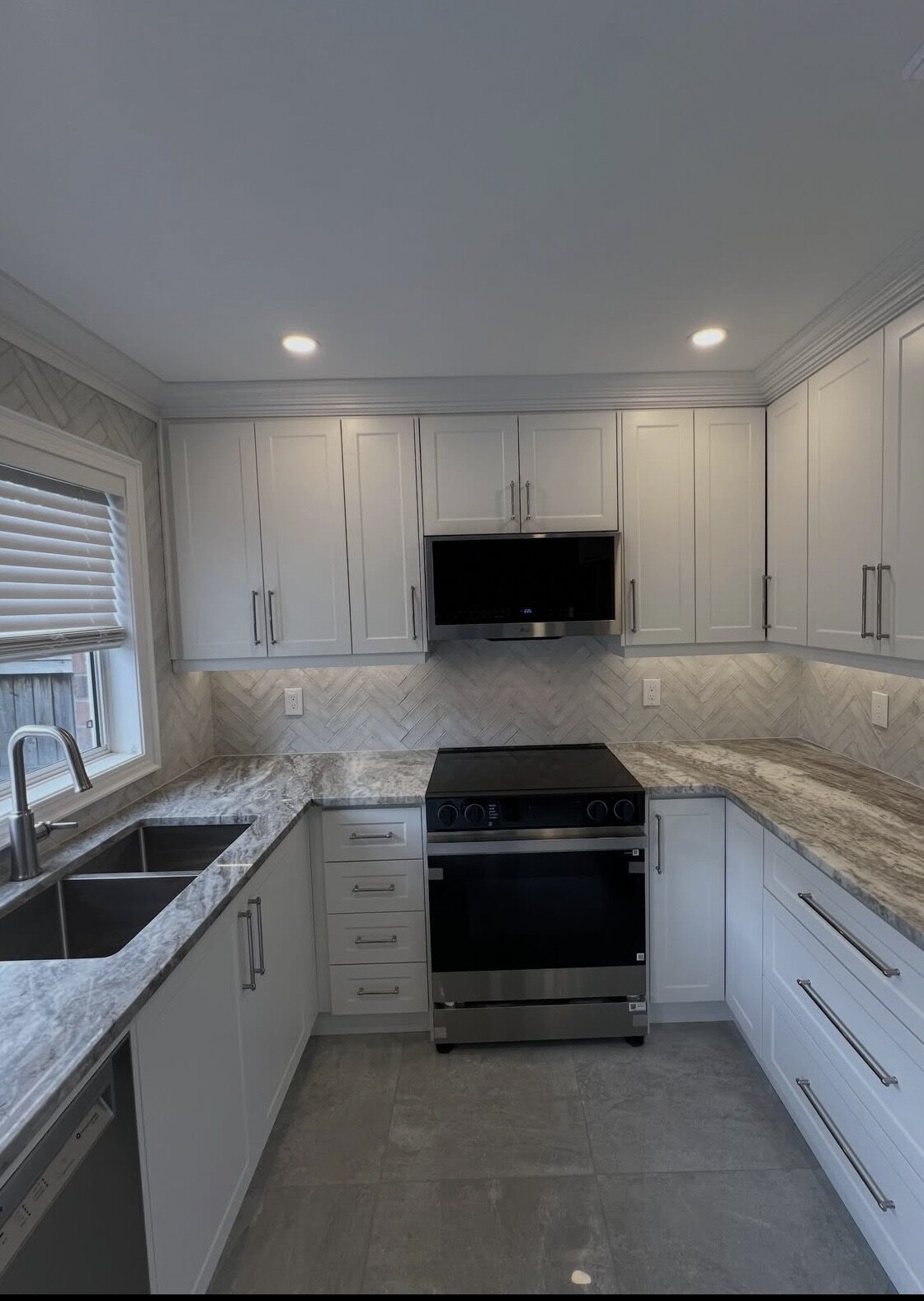 Same kitchen after renovation by Sarasota Building Co. — new cabinetry, herringbone backsplash, and updated countertops